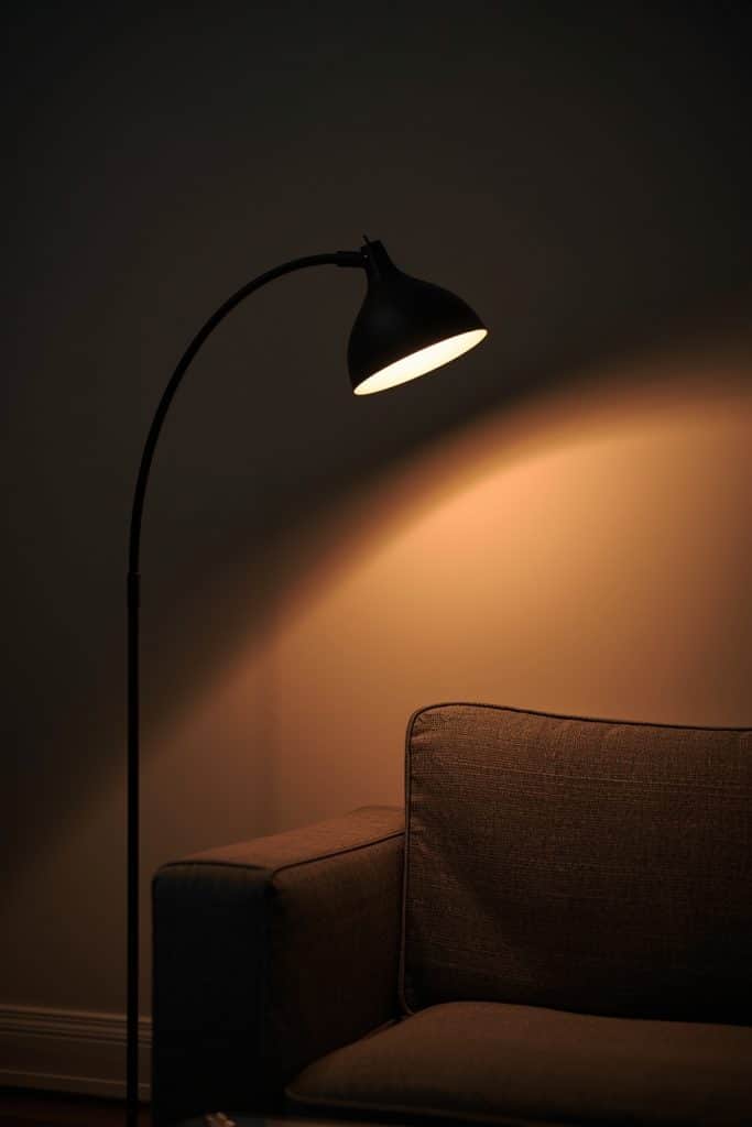 Arc floor lamp over sofa casting warm cone light in moody evening living room
