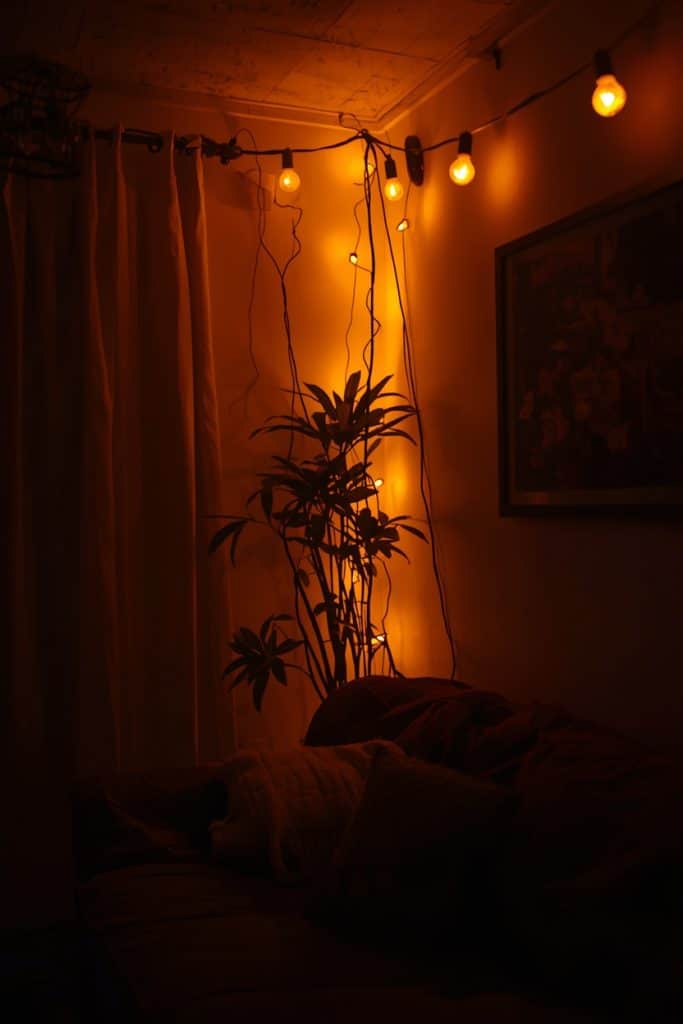 Small living room illuminated solely by warm string lights along the ceiling, creating a soft glowing and intimate low-light ambiance