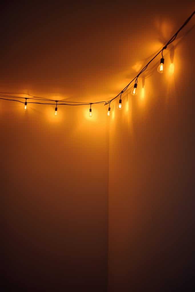 Warm string lights along ceiling edge creating a soft low glow cozy room ambiance
